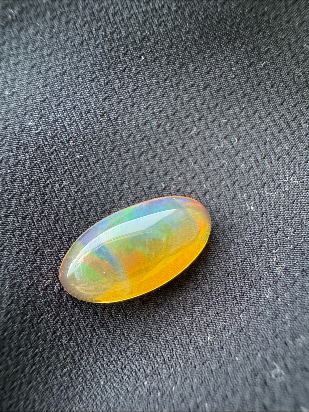 Yellow opal with green play of color in a long oval marquise cut cabochon